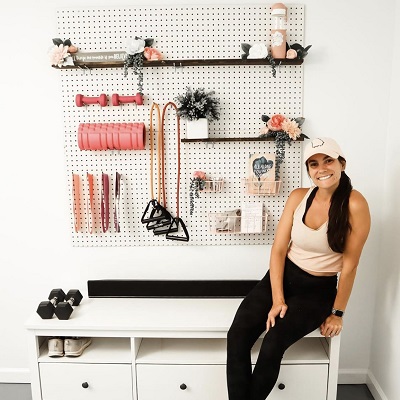 A woman sitting in front of a peg board and on which all the gym equipments are arranged